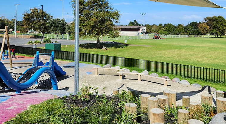 Ngā Hau Māngere / Māngere Centre Park - Section of the playground with the sports field and car park in the background.