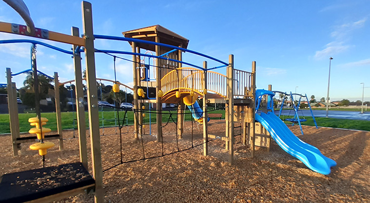 Meadowland Park - Section of the playground with climbing net, small double slide, climbing tower and bridge, and swinging seats.