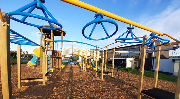 Meadowland Park - Looking through the middle of the playground with swinging and balancing equipment, bridge, slides and more.