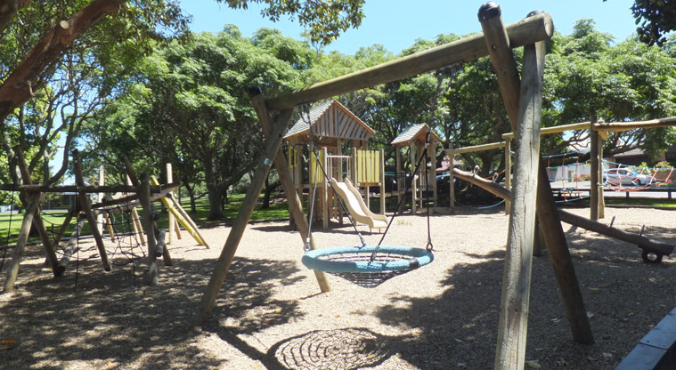 Melville Park - Wooden playground under the trees with climbing equipment, swings and slides. Photo credit: J Grigg.