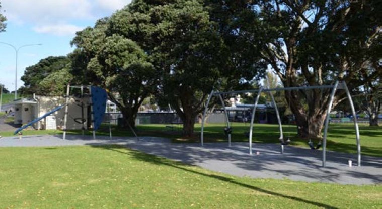 Narrow Neck Beach - Set of four swings with climbing equipment, trees and the toilets in the background.