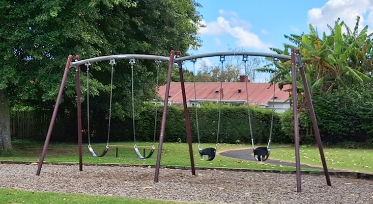 Orchard Reserve - Swing set with a section of path and trees in the background. Photo credit: T Hodder.