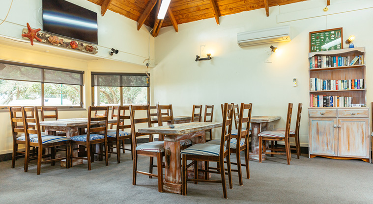 Ōrewa Beach Holiday Park – Dining area with a television on the wall.
