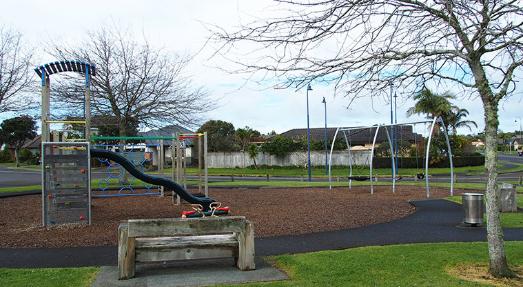 Paremuka Lakeside - Playground with climbing equipment, wobbly bridge, slide, swings and rocker toy and a seat in the foreground. Photo credit: Tracey Hodder.