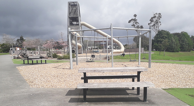 Parrs Park - Picnic table and seats with playground in the background.