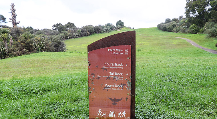 Point View Reserve - A directional sign with open grassed space and a section of gravel path in the background.