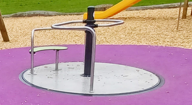 Ponderosa Reserve - Accessible carousel surrounded by bright pink rubber surfacing.