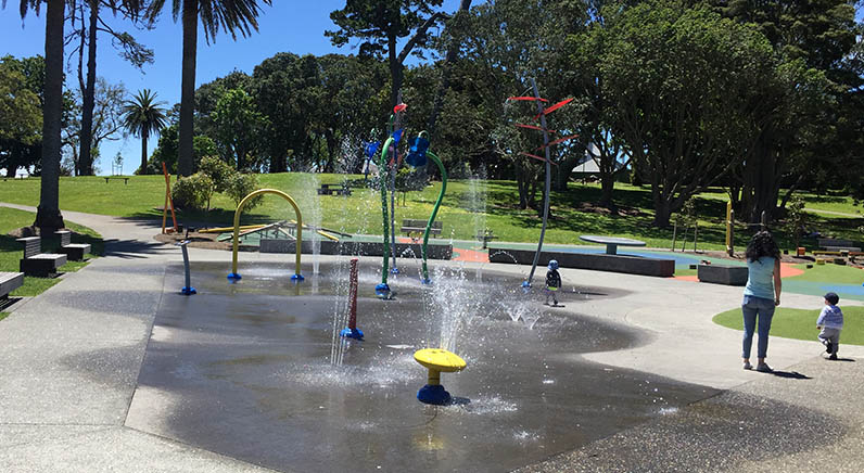 Potters Park – The splash pad with seating around the outside and large established trees in the background.