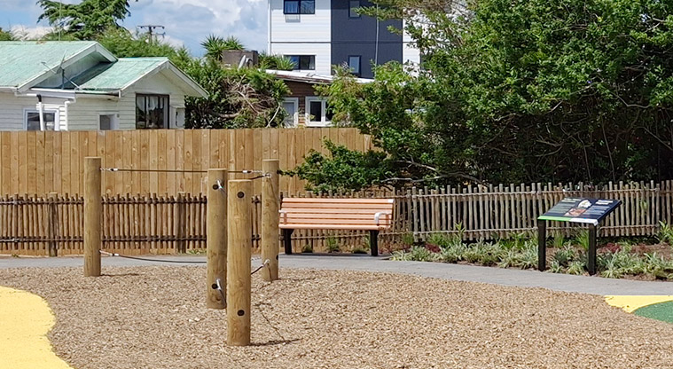 Rānui Domain - Balance rope course with a bench seat, path and information board in the background.
