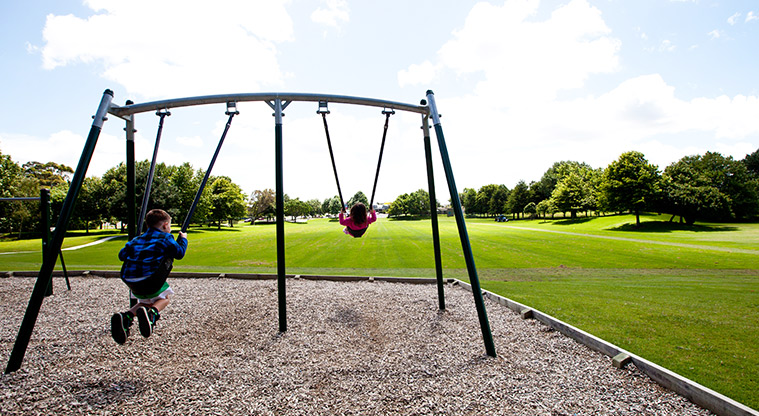 Otaawhati / Ray Small Park - Children on the swings with sports fields and trees in the background. Photo credit: Theo Leach.