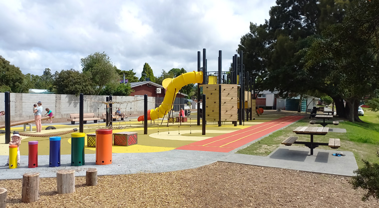 Riverhead War Memorial Park - Balancing logs and climbing nets in front of the playground while towards the right is a line of picnic tables by a short running track.