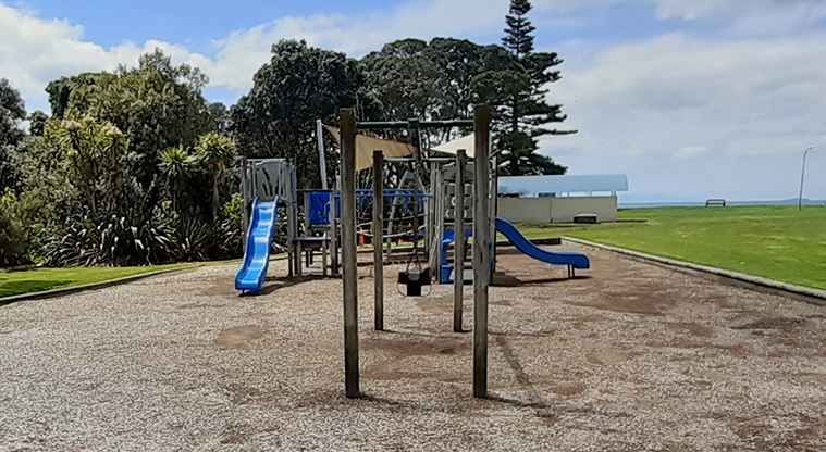 Rothesay Bay Beach Reserve - Playground with the toilet block and beach in the background.