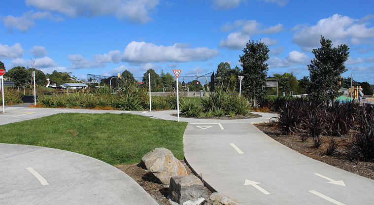 Royal Reserve - Wide "learn to ride" tracks with road markings and Give Way signs, with gardens and the basketball court in the background.
