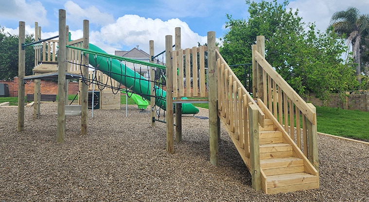 Santa Cruz Park - Steps leading up to the first platform of the high play module, with the rest of the playground in the background.