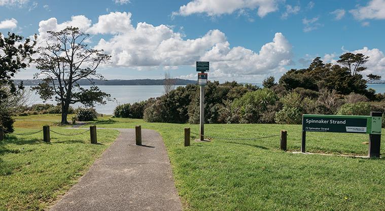 Spinnaker Strand - Sign at the entrance with views over the Waitematā Harbour.