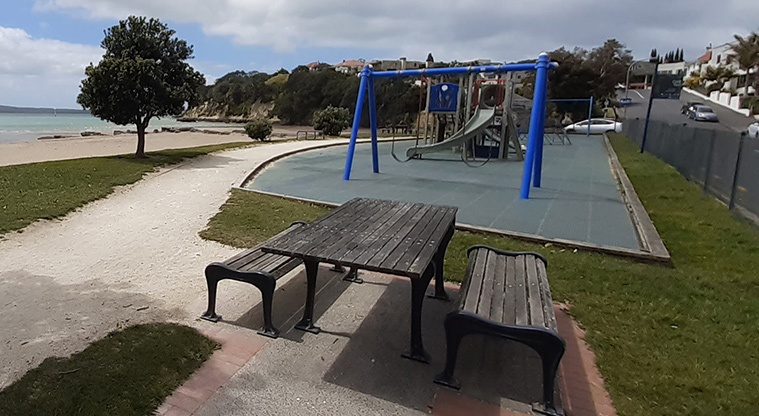 St Heliers Bay Beach Reserve - Picnic table and playground with the beach in the background.
