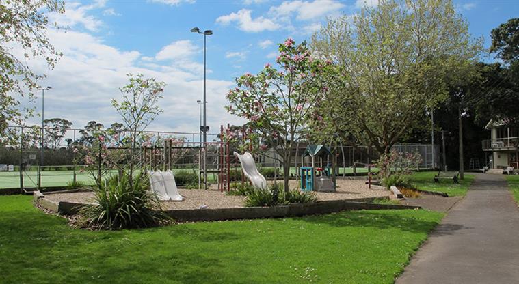Stanley Bay Park - Playground with slides, climbing equipment and toddler play unit, surrounded by grass space and trees.