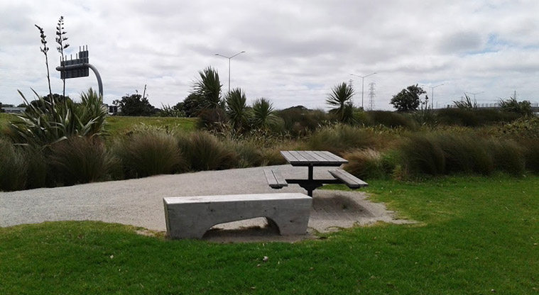 Taumanu Reserve - Picnic table and seating with flax and trees in the background.