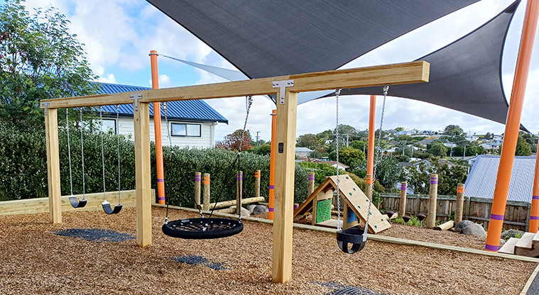 Taurus Crescent Reserve - Swing set with two belt swings, a bucket swing and a basket swing, with the cubby house, balance beams and steppers in the background.