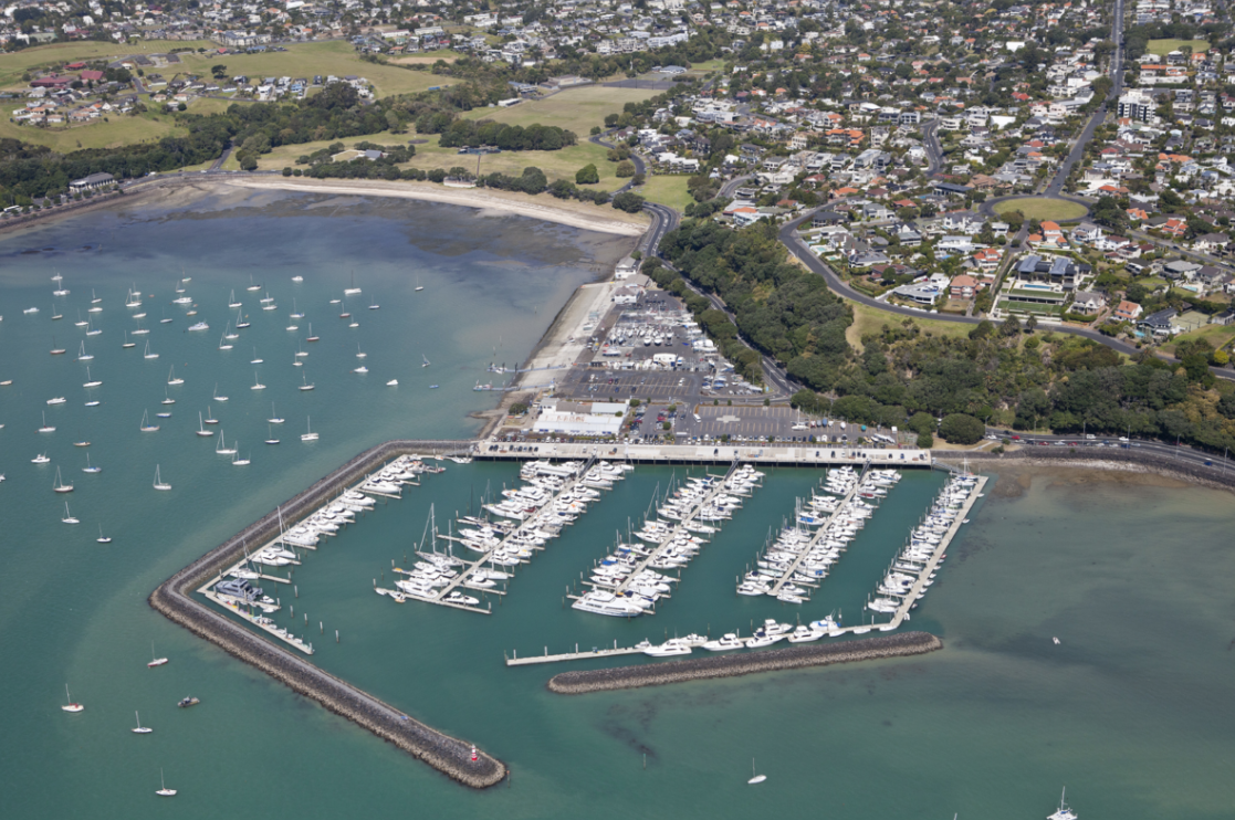 Aerial view of a marina with full carpark and rows of docked boats.