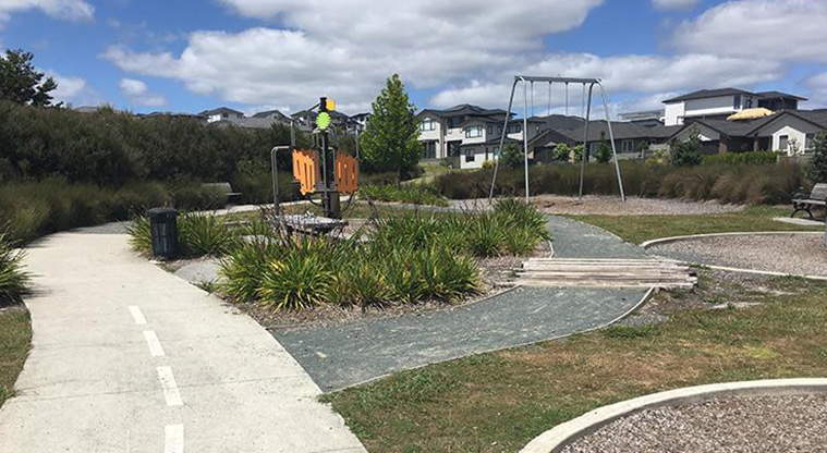 Timberlands Reserve - Section of the a learn-to-ride path on the left, gardens in the foreground and a climbing frame and swings in the background.