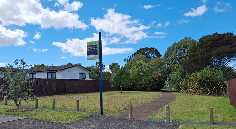 Tony Segedin Esplanade Reserve - Sign at the entrance to the reserve from Tony Segedin Drive with a path and trees in the background. Photo credit: T Hodder.