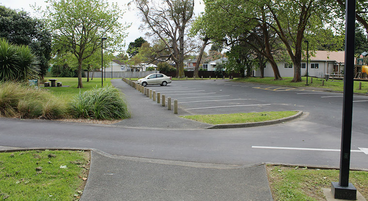 Tūī Glen Reserve - Section of one of the car parking areas with the small playground and Scout Hall on the right, and open space and trees on the left.