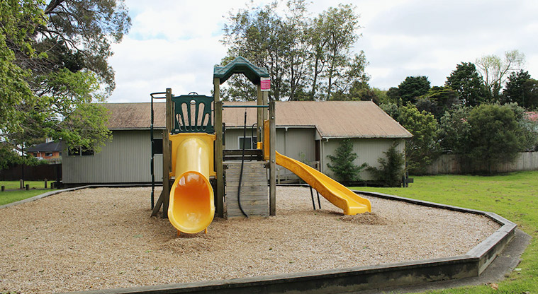 Tūī Glen Reserve - Small play module for younger children with climbing wall, platforms, and two yellow slides.