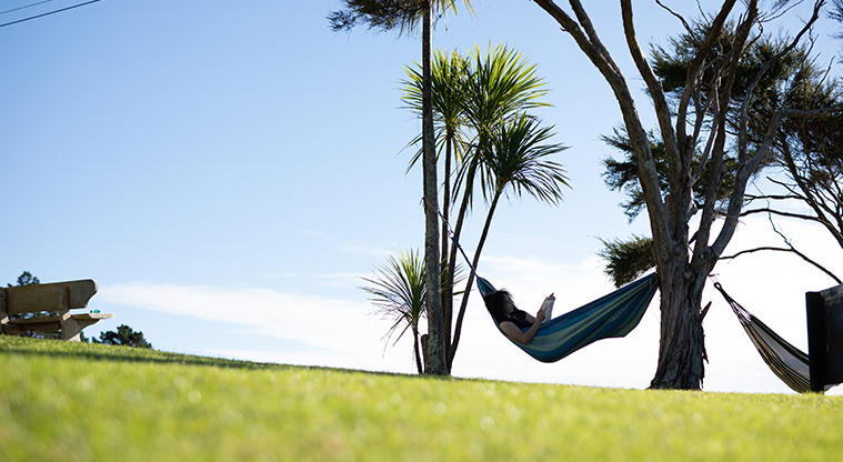 Waiheke Backpackers Hostel - Person relaxing in a hammock is the hostel grounds.
