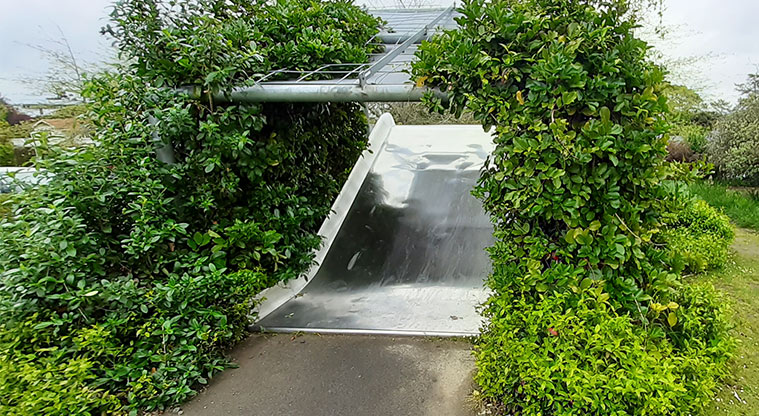 Wainoni Park North - Metal slide with plants growing up the sides and over the top.