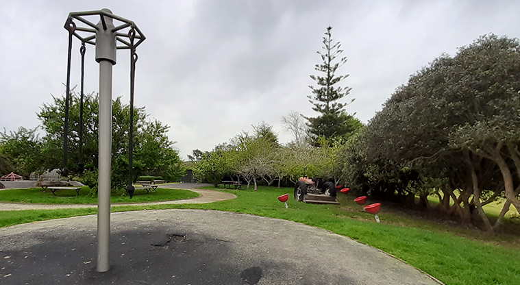 Wainoni Park North - Hanging rope swing with the spinning eggcups, tractor, open space and trees in the background.