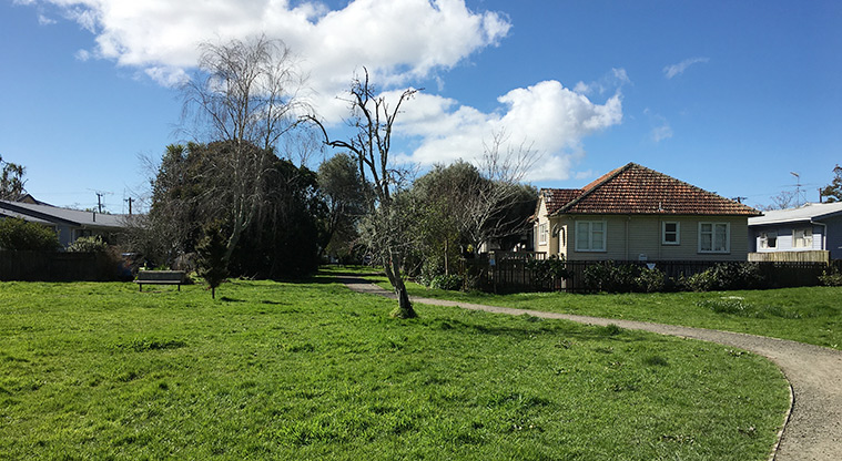 Watea Reserve - Section of path leading to the entrance, with grass, trees and a bench seat on the left. Photo credit: S Hulse.