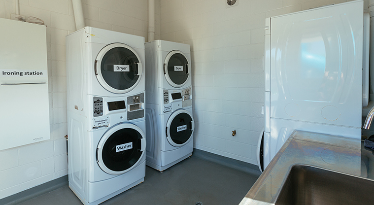 Whangateau Holiday Park - Laundry with washing machines, dryers and ironing station.