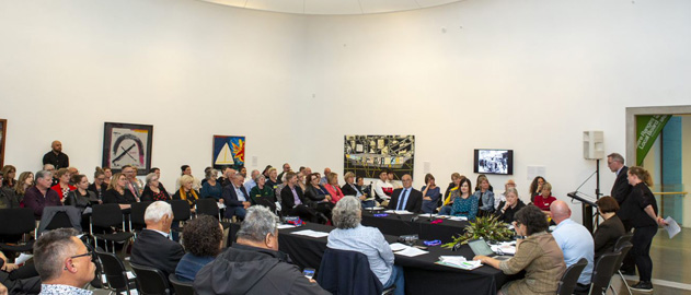 A large group of people seated at a meeting inside a building.