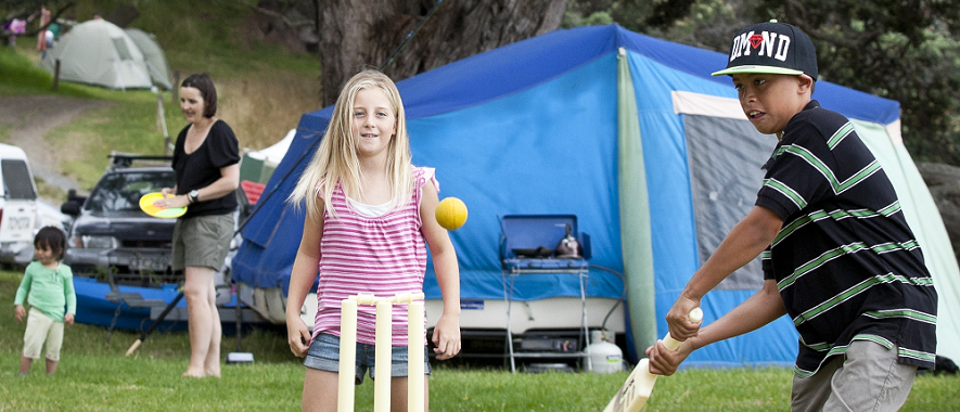 Children playing cricket at a campground. 
