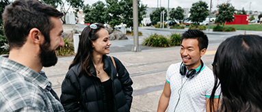 Photo of a group of four people standing and chatting.