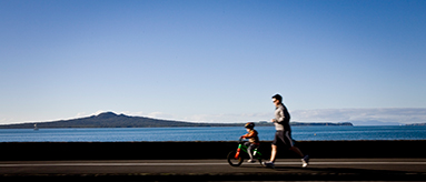 Photo of a man running and a small child on a bike along Tamaki Drive.