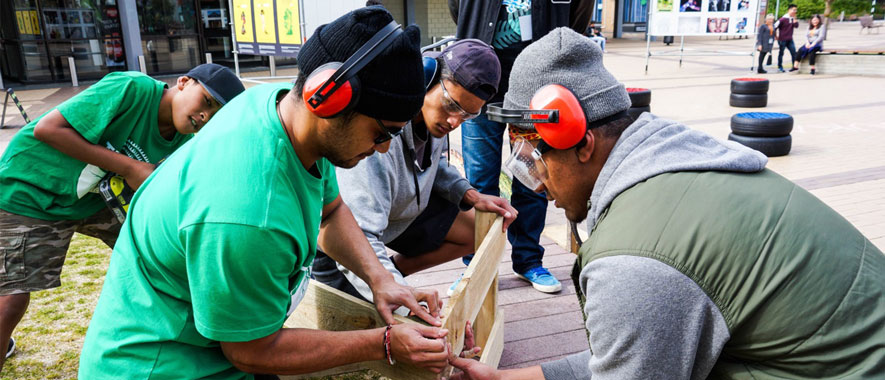 Photograph of four young men fixing a fence as part of fix it event in South Auckland