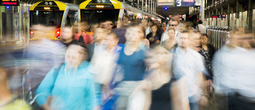 Photograph of a platform inside Britomart train station at morning peak time with lots of commuters walking towards the exit of the station.
