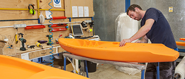 Photo of a man in a workshop building a kayak.