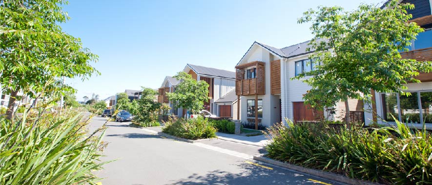 A row of modern townhouses on a leafy street.