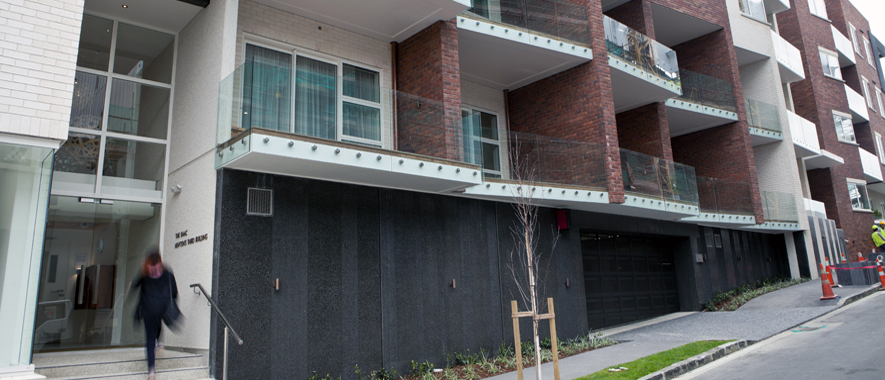 Woman enters the main door of a modern Auckland apartment block.