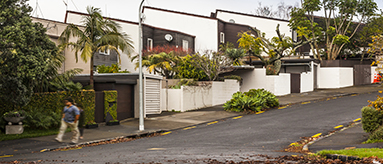 Photo of a person walking up a footpath past a block of townhouses.