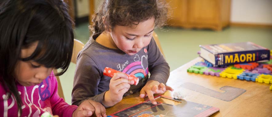 Young Māori girls learning at a table.