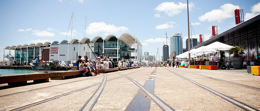People sitting and walking on Auckland Waterfront on sunny day