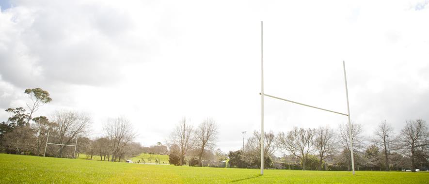 An empty sportsfield with two rugby goals on either end.